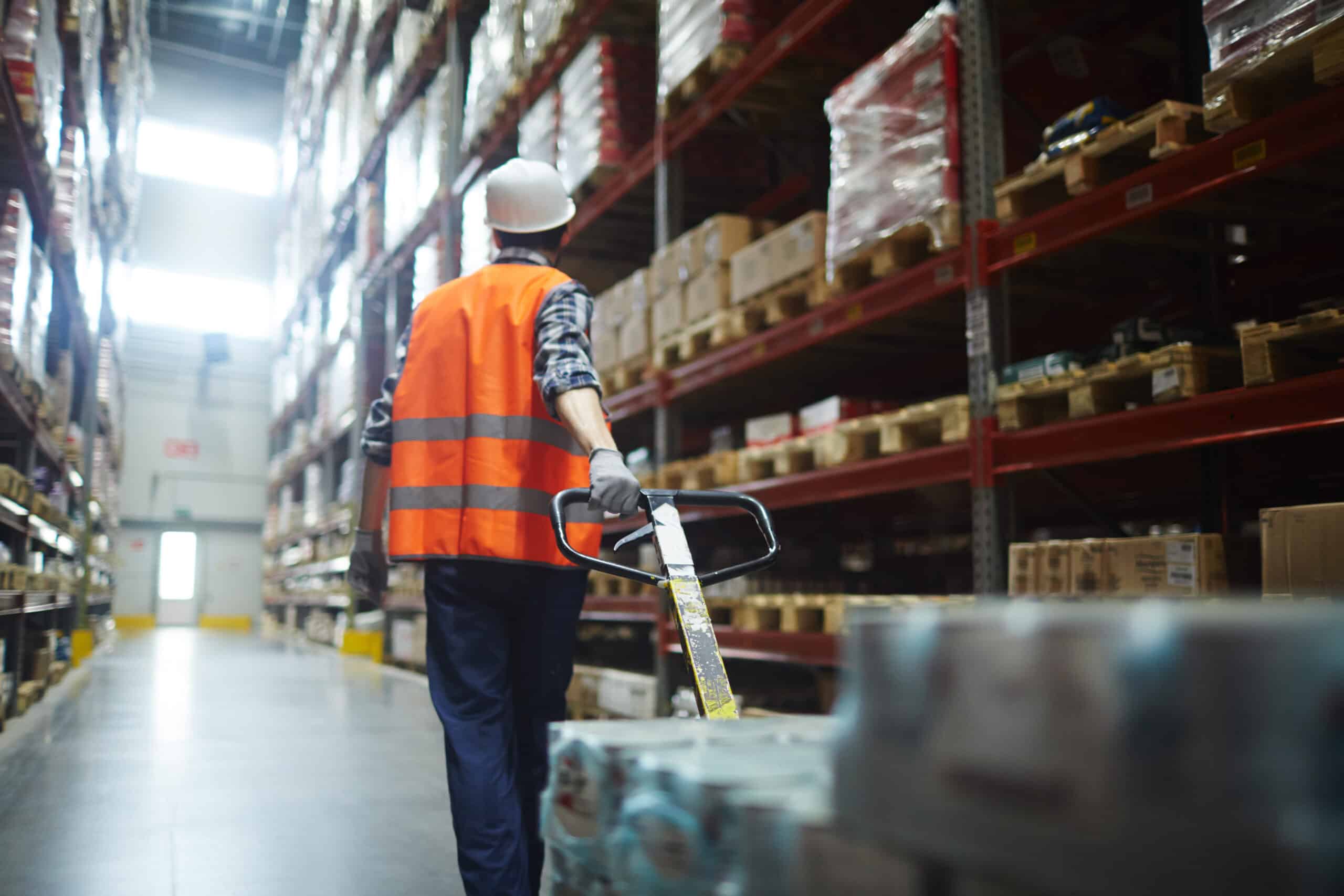 Pulling forklift Worker in helmet and uniform pulling forklift with packed goods.