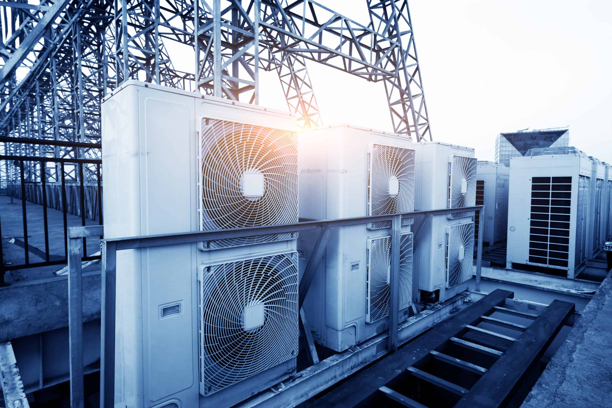 Air conditioner units (HVAC) on a roof of industrial building with blue sky and clouds in the background. Air conditioner units (HVAC) on a roof of industrial building with blue sky and clouds in the background.