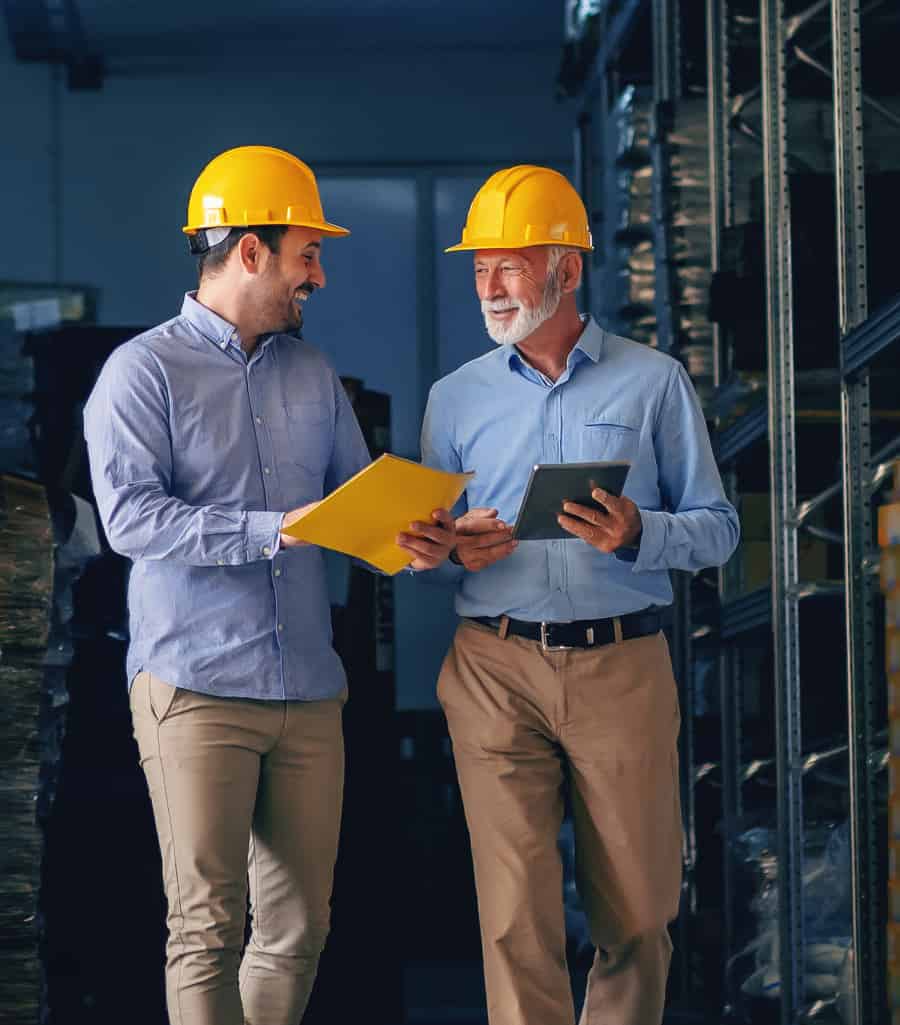professional-services Two colleagues chatting, they both wear a safety helmet and have a folder in their hands.