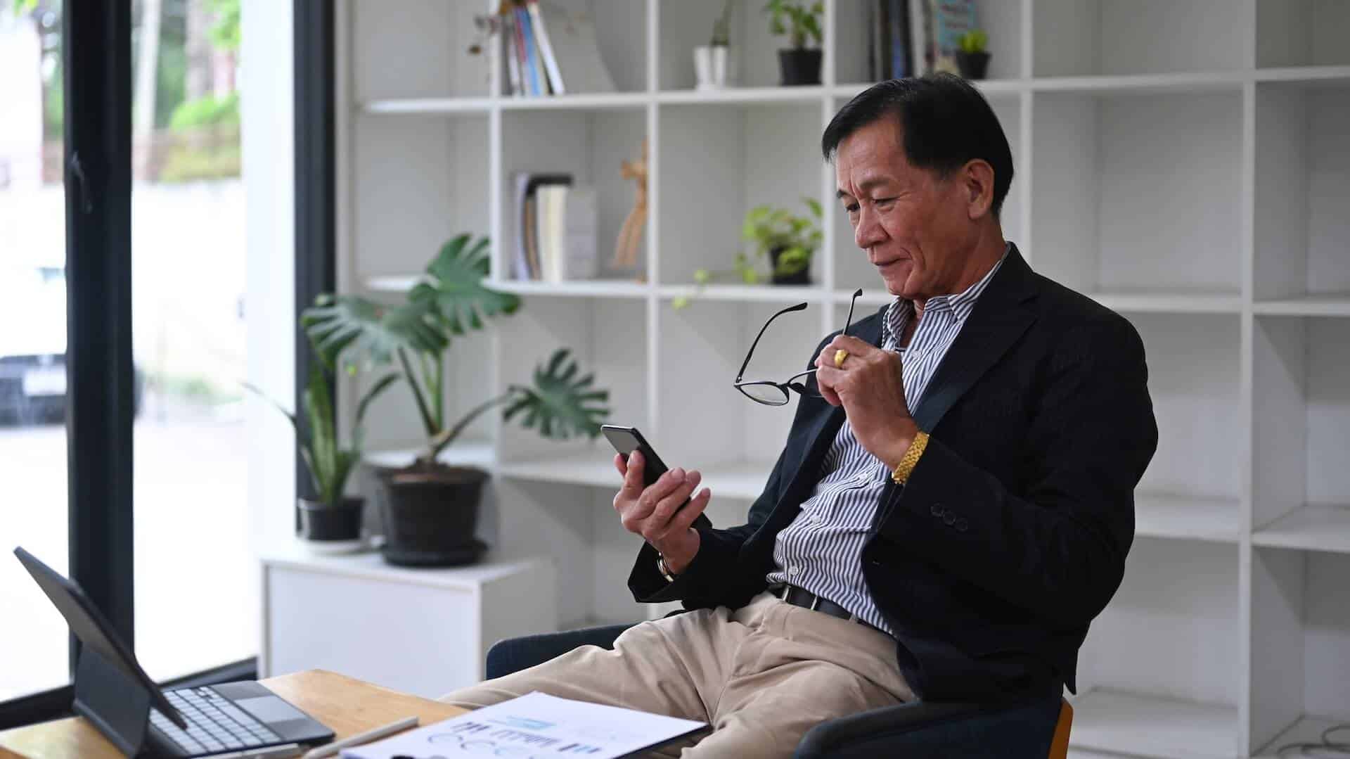 getty-images-V_Bo3VJhhoM-unsplash (1) An older person sitting, checking his phone.