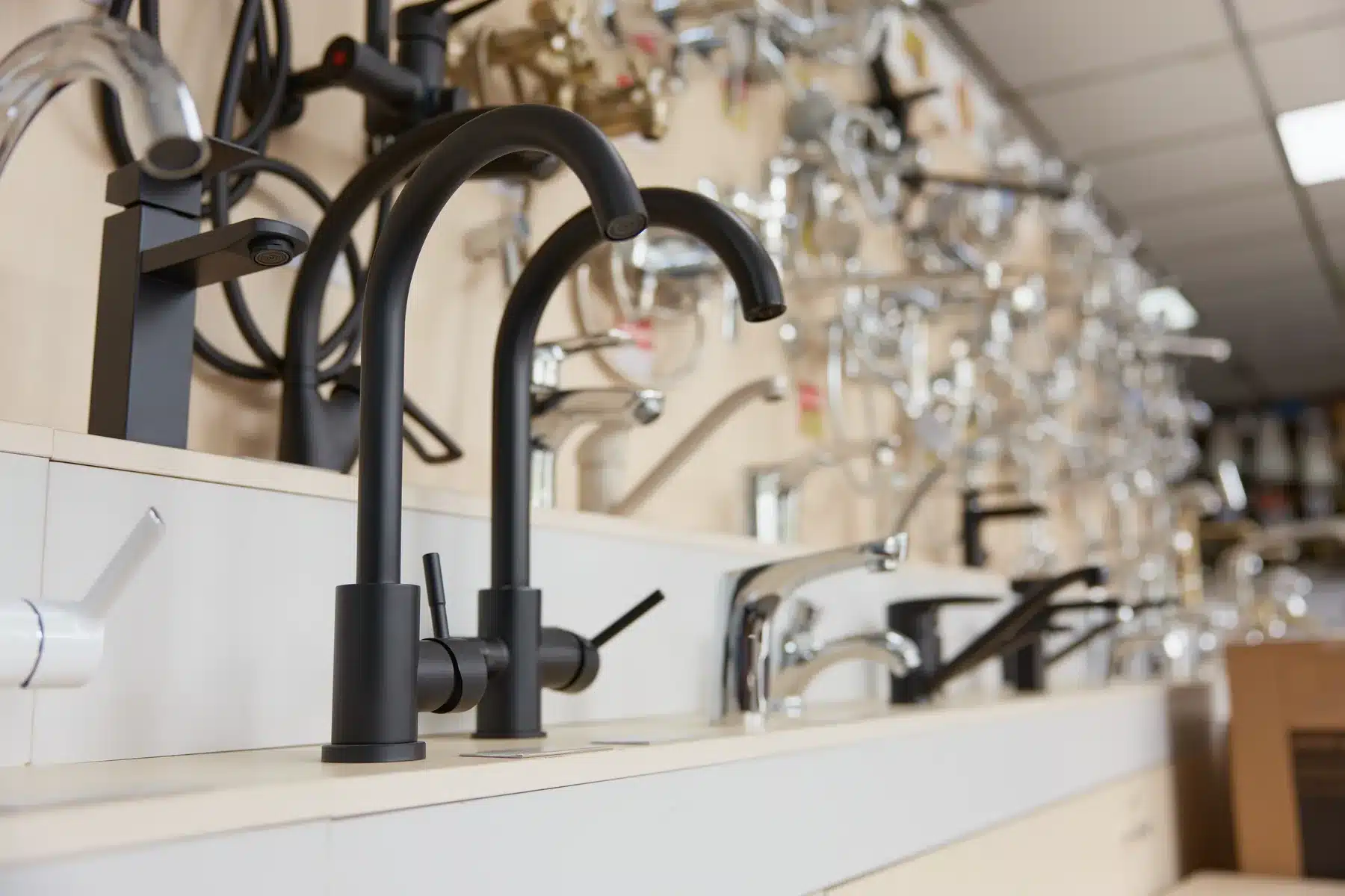 Faucet display wall in a kitchen and bath showroom, rows of matte-black and chrome fixtures