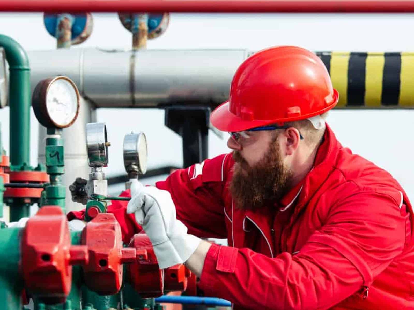 Pipe, valve and fitting technician working a manifold of gauges and valves